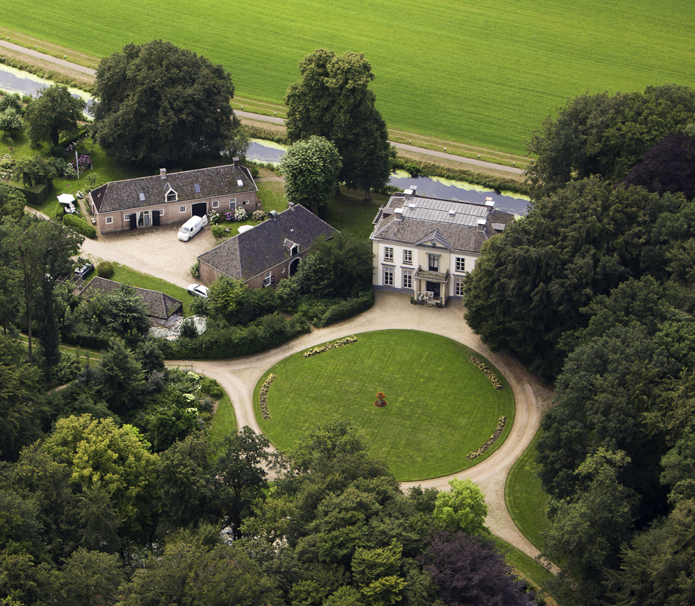 Het landgoed vanuit de lucht, met het landhuis en de ronde vijver.