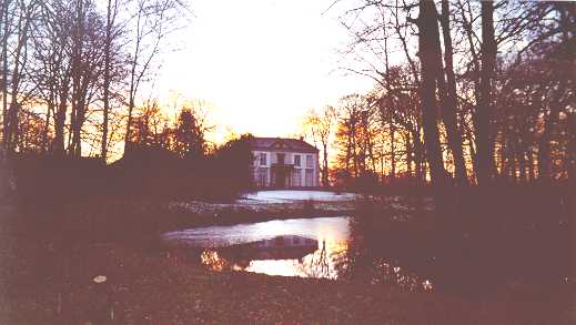 Het huis bij laagstaande zon, weerspiegeld in het water.